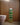 A handwoven Ghanaian toilet roll holder with a green and beige geometric pattern, displayed in a bathroom setting.