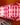A close-up of AARVEN's hanging paper light shade with a bold pink and white geometric pattern, set against a warm orange background.