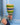 Hand holding a colourful woven rattle against a blue background