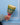 Hand holding a colourful woven rattle against a blue wall.