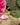 Handmade gold-tone brass rings on a stone surface with pink flowers and green leaves
