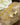 Gold chain necklace clasp with AARVEN logo on a stone surface