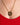 Gold necklace with a circular pendant on a person wearing a red garment.