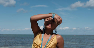 Woman shielding her eyes from the sun, standing in front of the sea