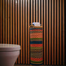 A handwoven multicolored toilet roll holder with a geometric pattern, placed in a bathroom setting.