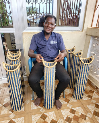 Person sitting on a chair holding a woven toilet roll holder with more in the background.