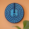 Blue decorative wall mask with geometric pattern on a peach wall.