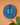 Blue decorative wall mask with geometric pattern on a peach wall.