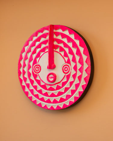 Fluoro Pink and White hand carved mini Ghanaian sun mask wall decor on peach background