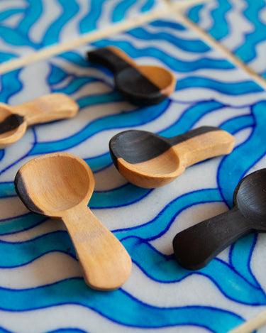 Wooden and black spoons on a blue and white wavy-patterned surface