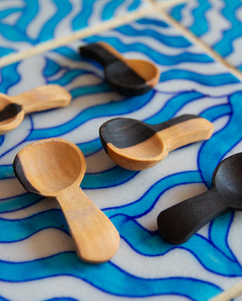 Wooden and black spoons on a blue and white wavy-patterned surface