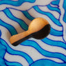 Wooden brush with black bristle head on a blue wavy patterned surface
