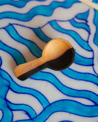 Wooden brush with black bristle head on a blue wavy patterned surface