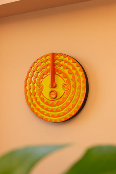 Decorative African sun mask in yellow and orange with geometric design on a peach wall