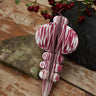 Decorative candy cane ornament on a wooden surface with red berries in the background