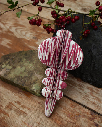 Decorative candy cane ornament on a wooden surface with red berries in the background