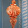 Decorative orange and white hanging ornament on a blue wall with white patterns.
