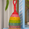 Rainbow woven rattle toy with a handle on a shelf