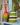 Two colourful woven musical shakers on a light blue surface with a blurred background