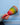 Hand holding a colourful rainbow woven rattle against a blue background