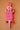 Hand carved Ghanaian crocodile mask with fluoro pink and white geometric patterns on a peach art wall