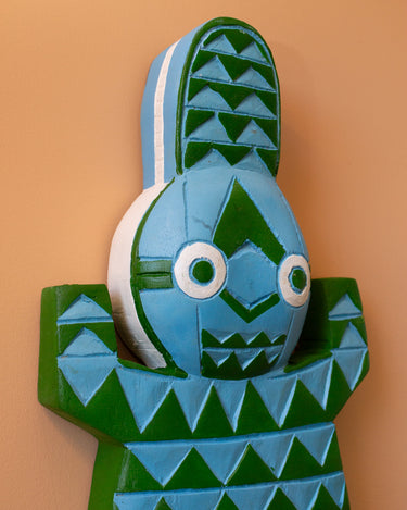 Decorative hand carved crocodile wall art with a blue and green geometric design on a peach background