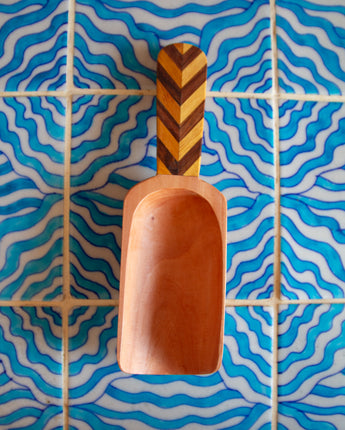 Wooden scoop on a blue and white wavy tile background