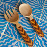 Wooden fork and spoon with chevron pattern handles on a blue wavy background