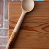 Wooden ladle on a wooden surface with a brick wall background