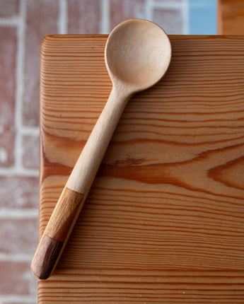Wooden ladle on a wooden surface with a brick wall background