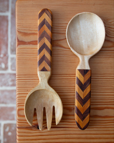 Wooden fork and spoon with chevron pattern handles on a wooden surface.