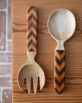 Wooden fork and spoon with chevron pattern handles on a wooden surface.