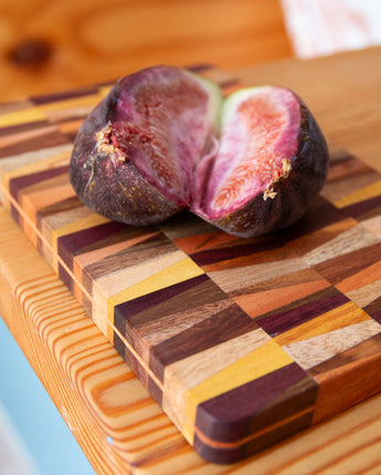Two figs on a multicolored wooden cutting board