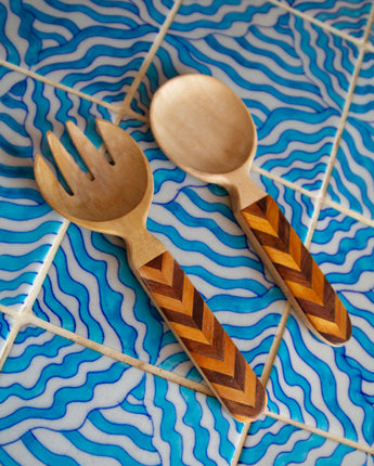 Wooden fork and spoon with chevron pattern handles on a blue wavy background