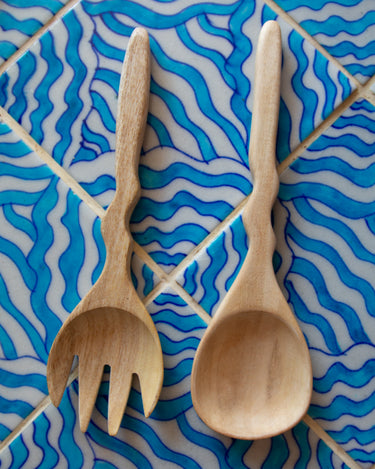 Wooden spoon and fork on a blue and white patterned tile background