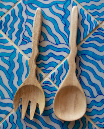 Wooden spoon and fork on a blue and white patterned tile background