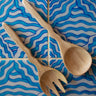 Wooden spoon and fork set on a blue and white wavy tile pattern