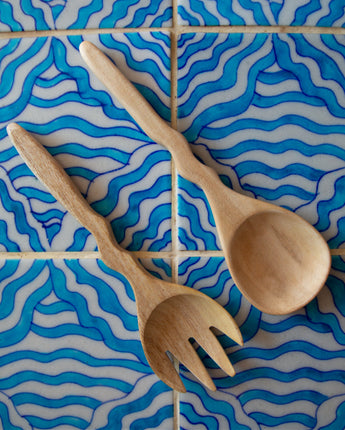 Wooden spoon and fork set on a blue and white wavy tile pattern