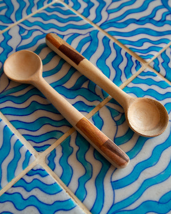 Two wooden spoons on a blue and white tiled surface