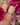 Gold ring on a finger with pink flowers in the background