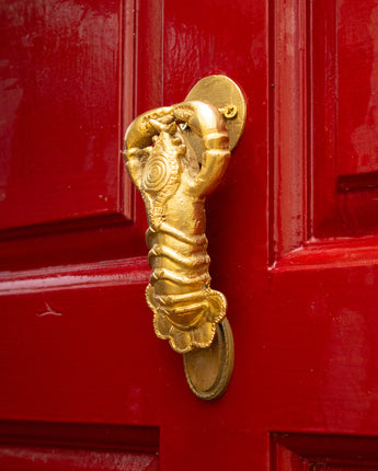 Gold lobster-shaped door knocker on a red door