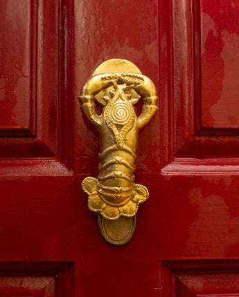 Gold lobster shaped novelty door knocker on a red door
