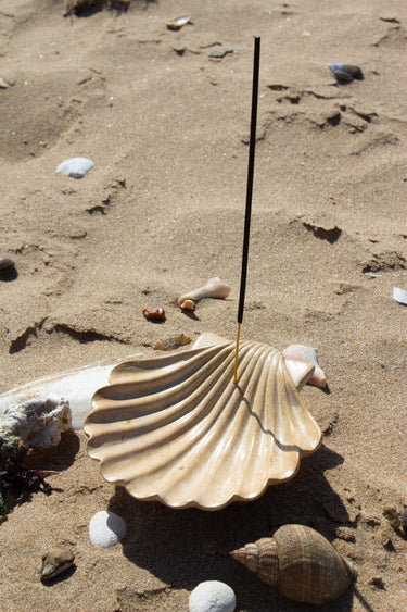 Shell incense burner with a stick on a sandy surface, handmade by artisans in Kenya from soapstone for AARVEN.