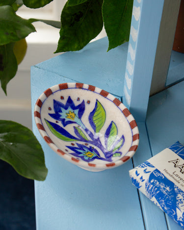 Decorative ceramic soap dish with floral design on a blue surface
