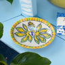 Decorative ceramic soap dish by AARVEN with floral design on a blue surface with plants