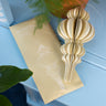Handmade paper hanging decoration on a blue surface with a plant in the background