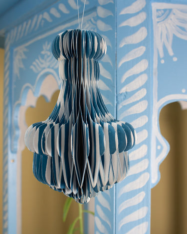 Blue and white striped paper honeycomb decoration hanging against a decorative wall.