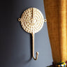 Solid brass wall hook with traditional sun mask pattern for home decor