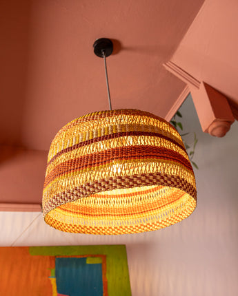 Woven pendant light hanging from a ceiling with a colourful artwork below.