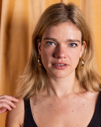 AARVEN Kilifi hoop earrings made of hammered brass with textured finish.